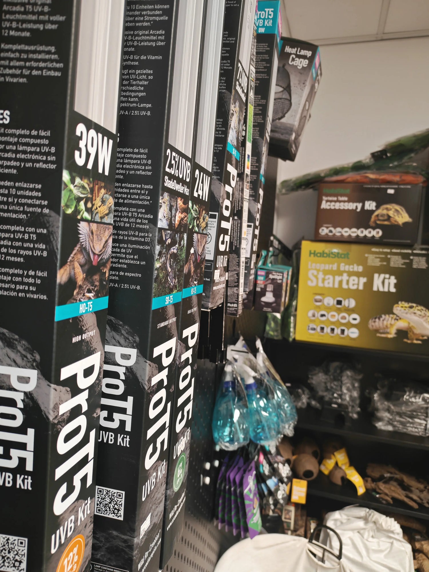 Shelves in a pet store displaying reptile UVB lighting products, including ProT5 bulbs, with starter kits and accessories in the background